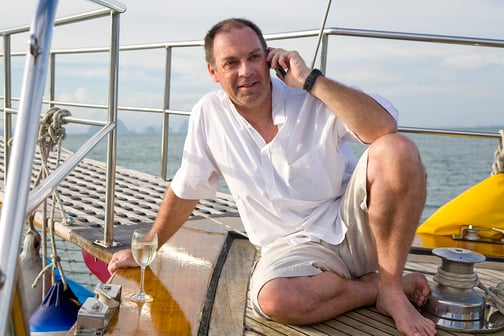 Man on yacht with mobile phone and wine